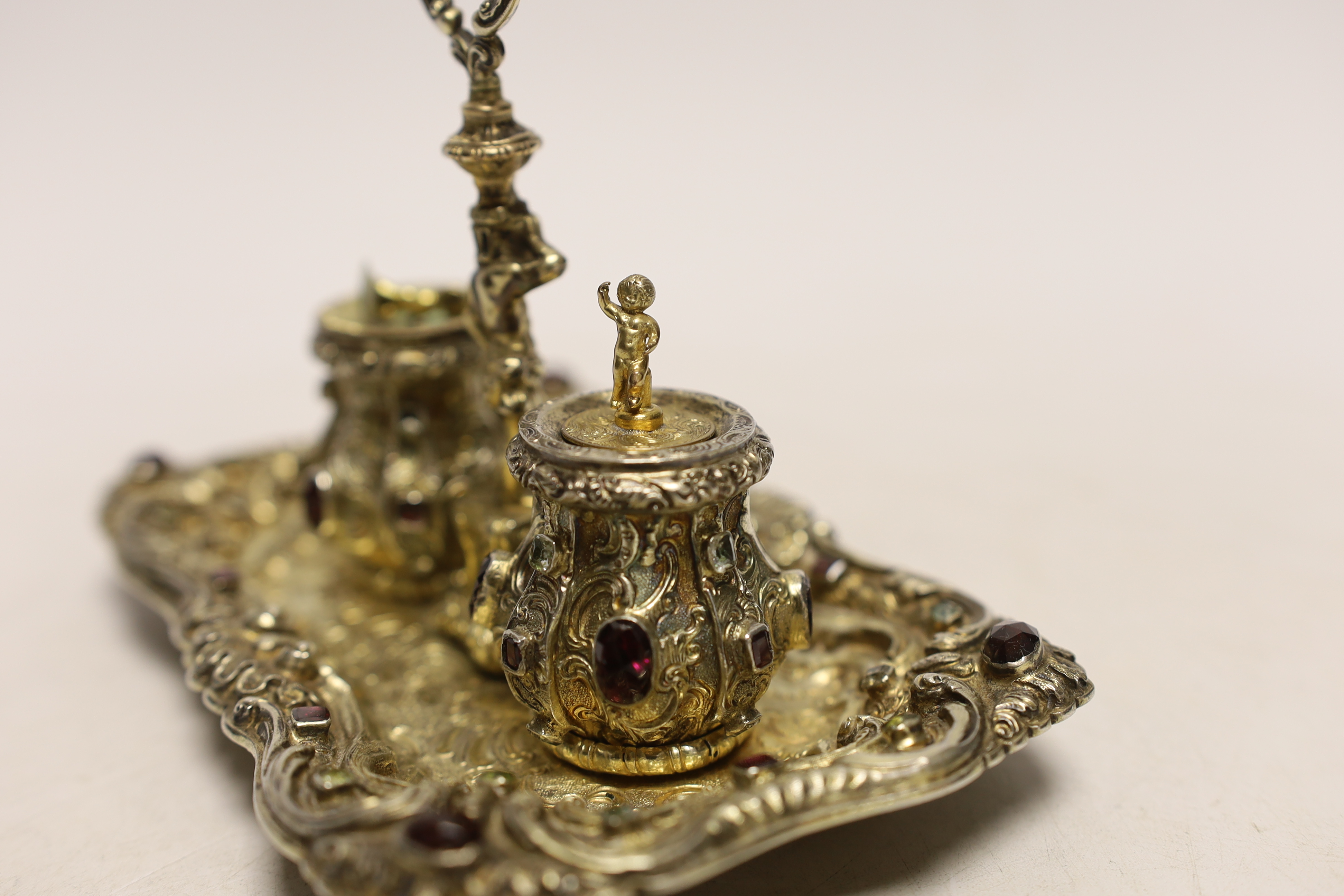 A 19th century Austrian embossed gilt white metal and multi gem set rectangular inkstand, with ring handle and two wells, 14.2cm, gross weight 6.3oz (a.f.).